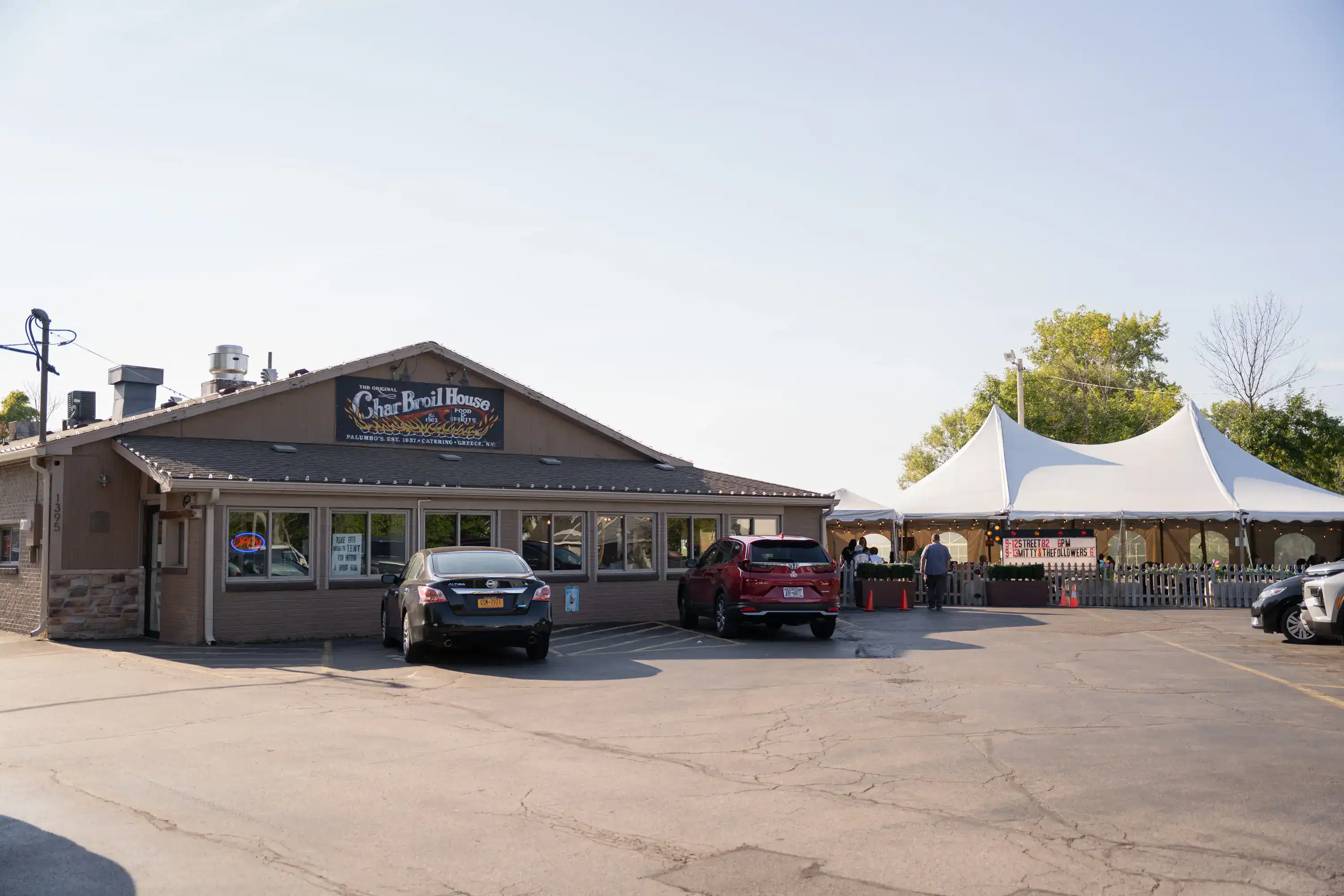 The Original Charbroil House restaurant with outdoor white tent seating area and parking lot