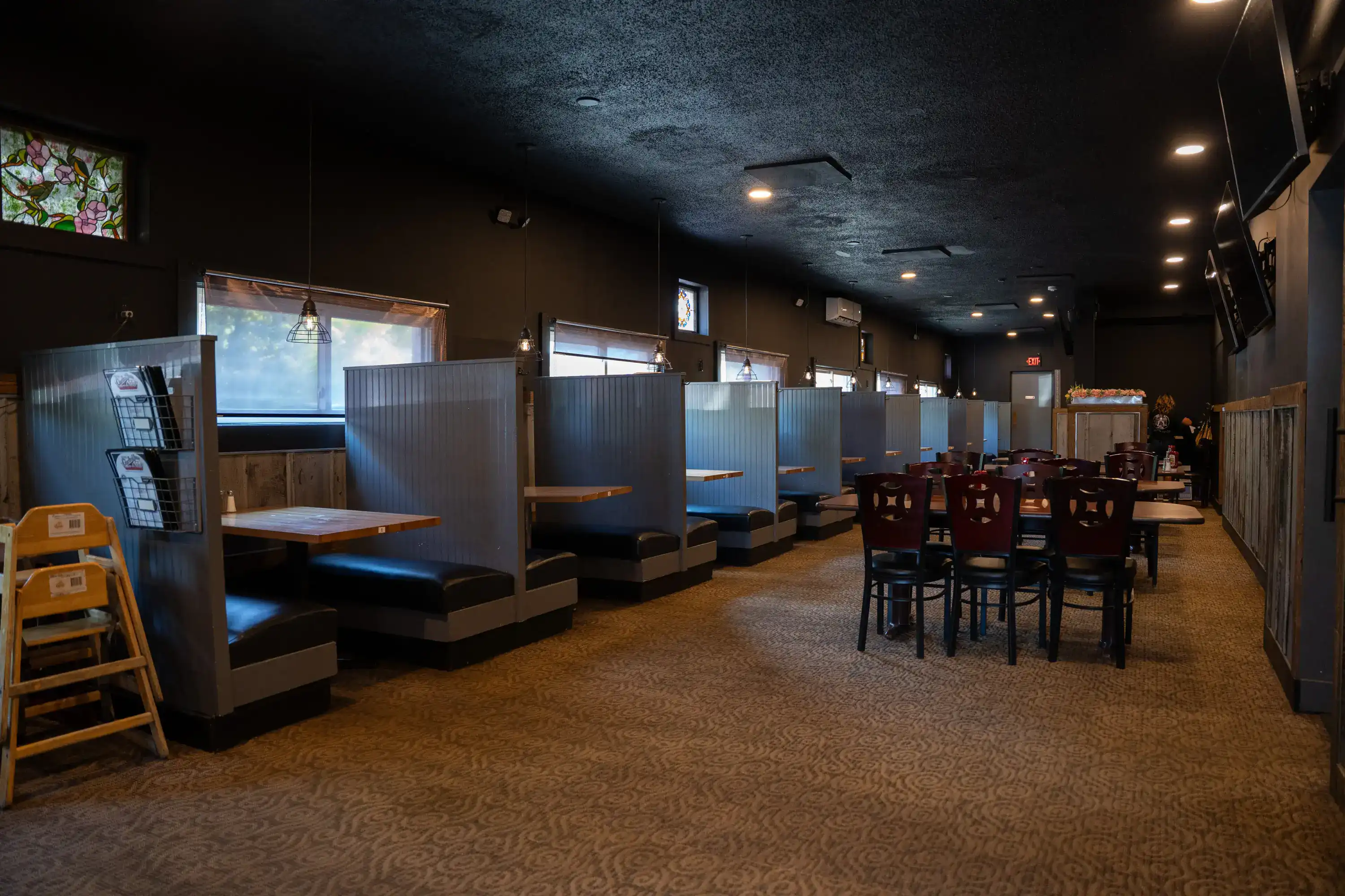Restaurant interior with booth seating along wall and wooden tables with dark chairs