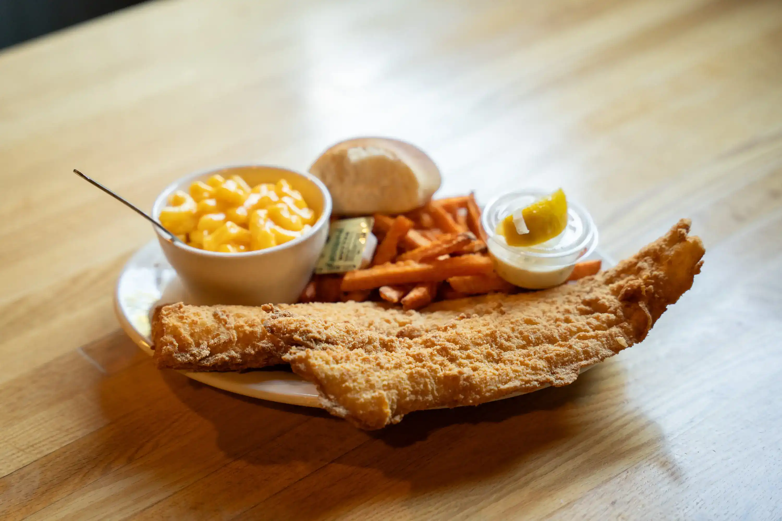 Fried fish with mac and cheese, sweet potato fries, pickles, and dinner roll