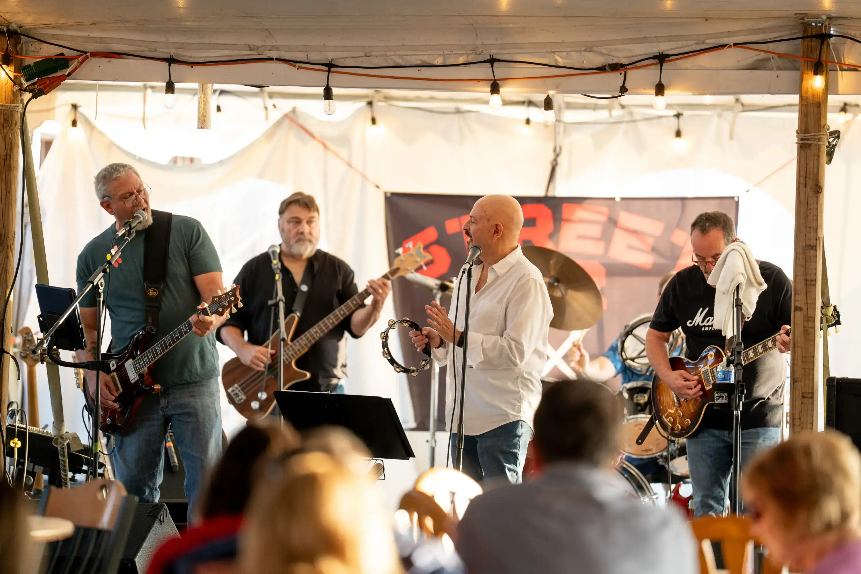 Band performing under white tent with string lights for diners at The Original Charbroil House