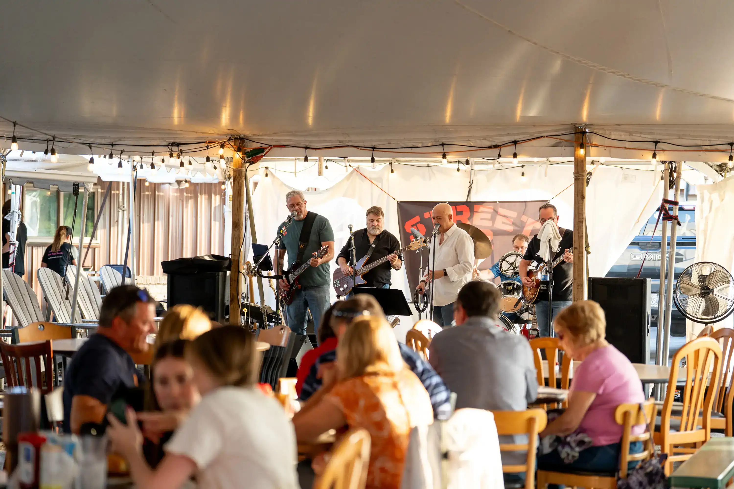 Band performing under tent at The Original Charbroil House with diners at tables