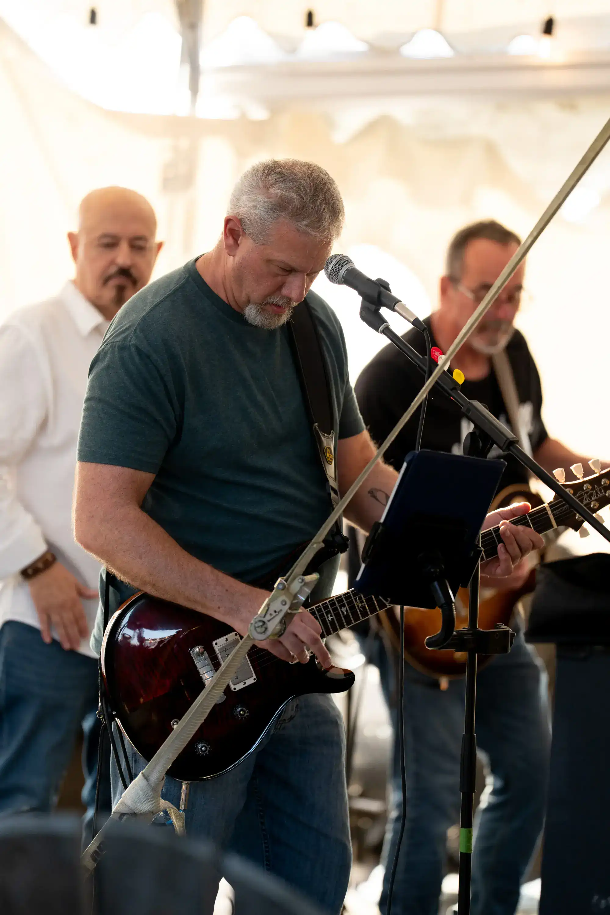 Guitarist performing with microphone at The Original Charbroil House outdoor tent event