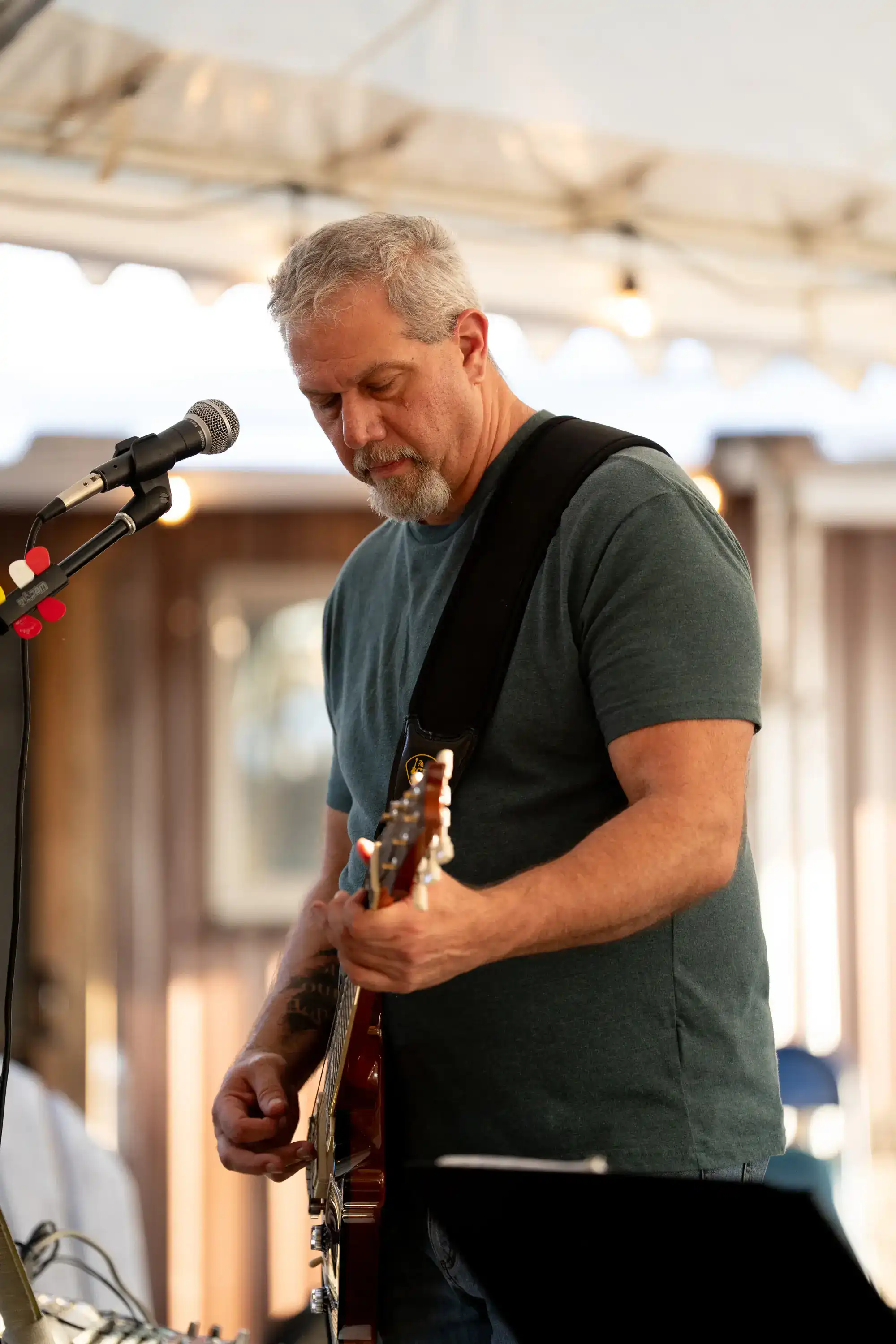 Guitarist performing live music under white tent canopy with microphone