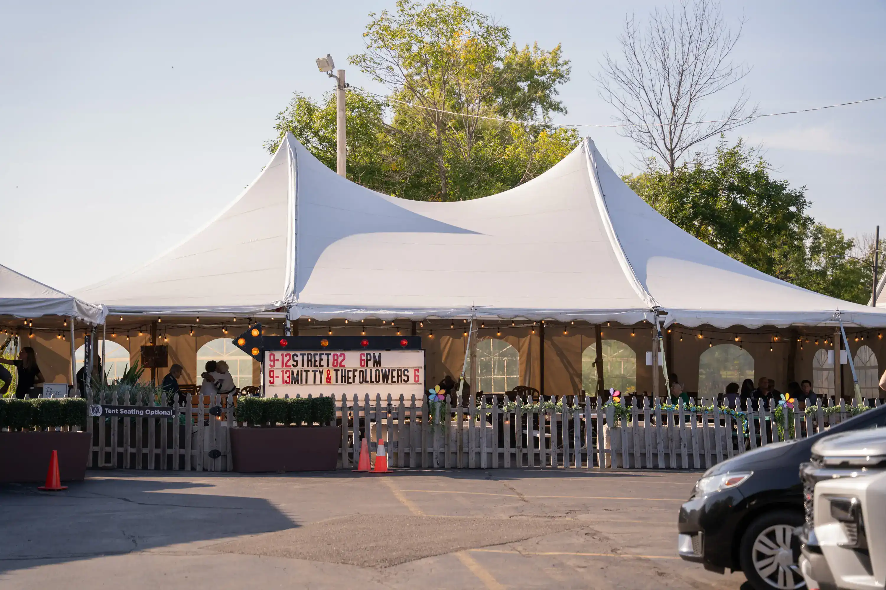 White tent with banner reading '9-12 STREET82 6PM 9-13 MITTY & THE FOLLOWERS 6' and string lights
