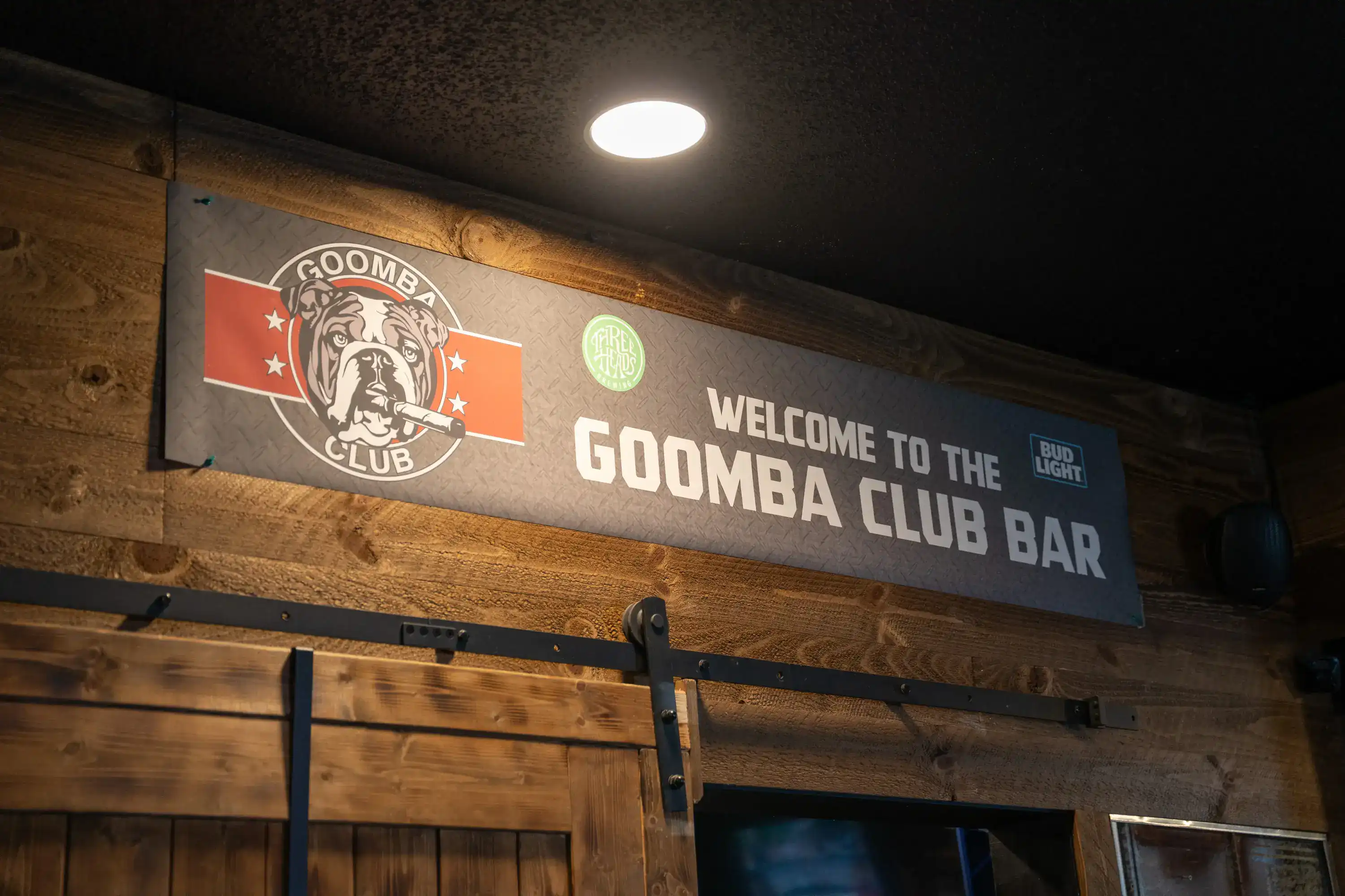Welcome to the Goomba Club Bar sign with bulldog logo on rustic wooden wall